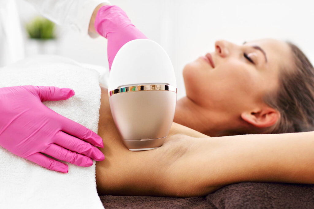Woman receiving laser hair removal treatment with professional device.