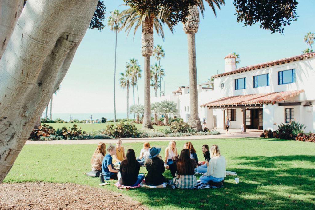 a group of people sitting on a bench in front of a house