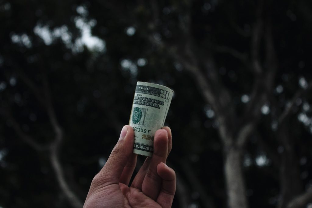 a hand holding a stack of dollar bills