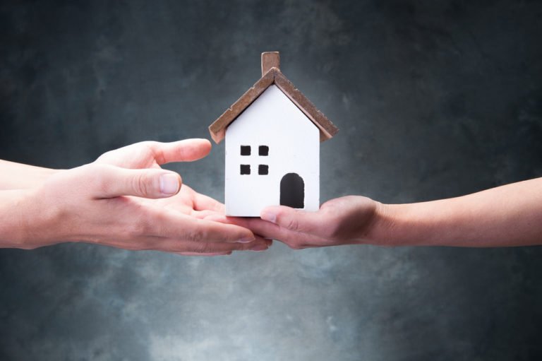 a person's hand holding a small house