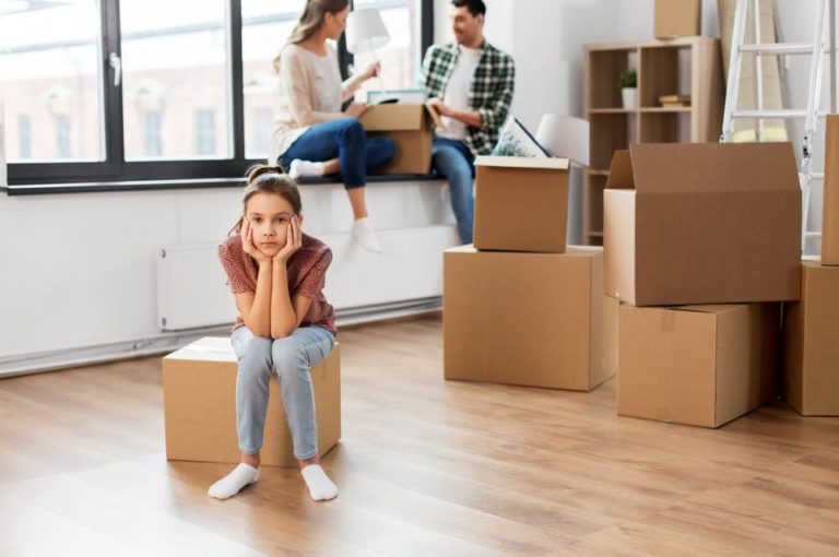 a girl sitting on a chair in a room with a few people