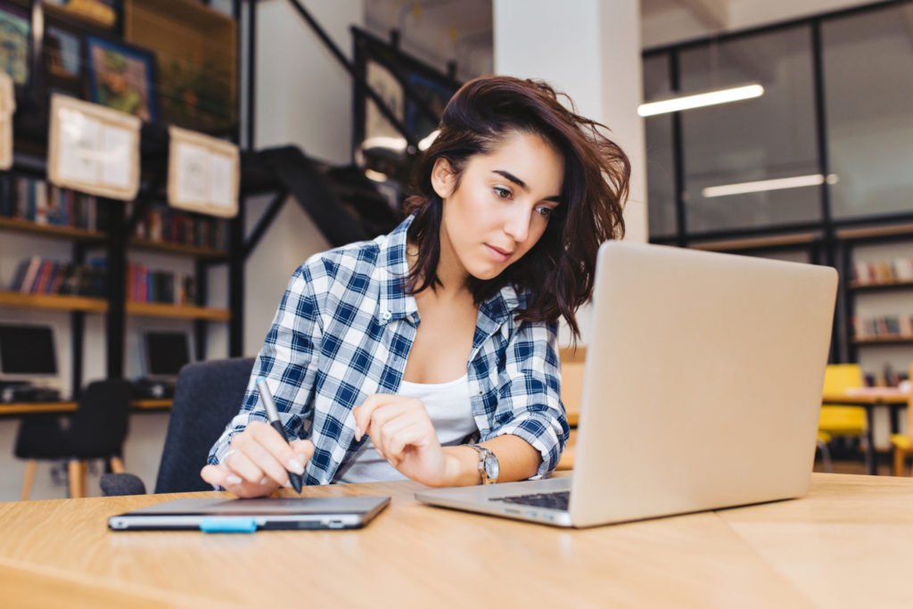 a woman sitting at a table with a laptop