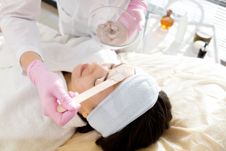 a person in a white bathrobe with a pink glove and a white glove on the hand