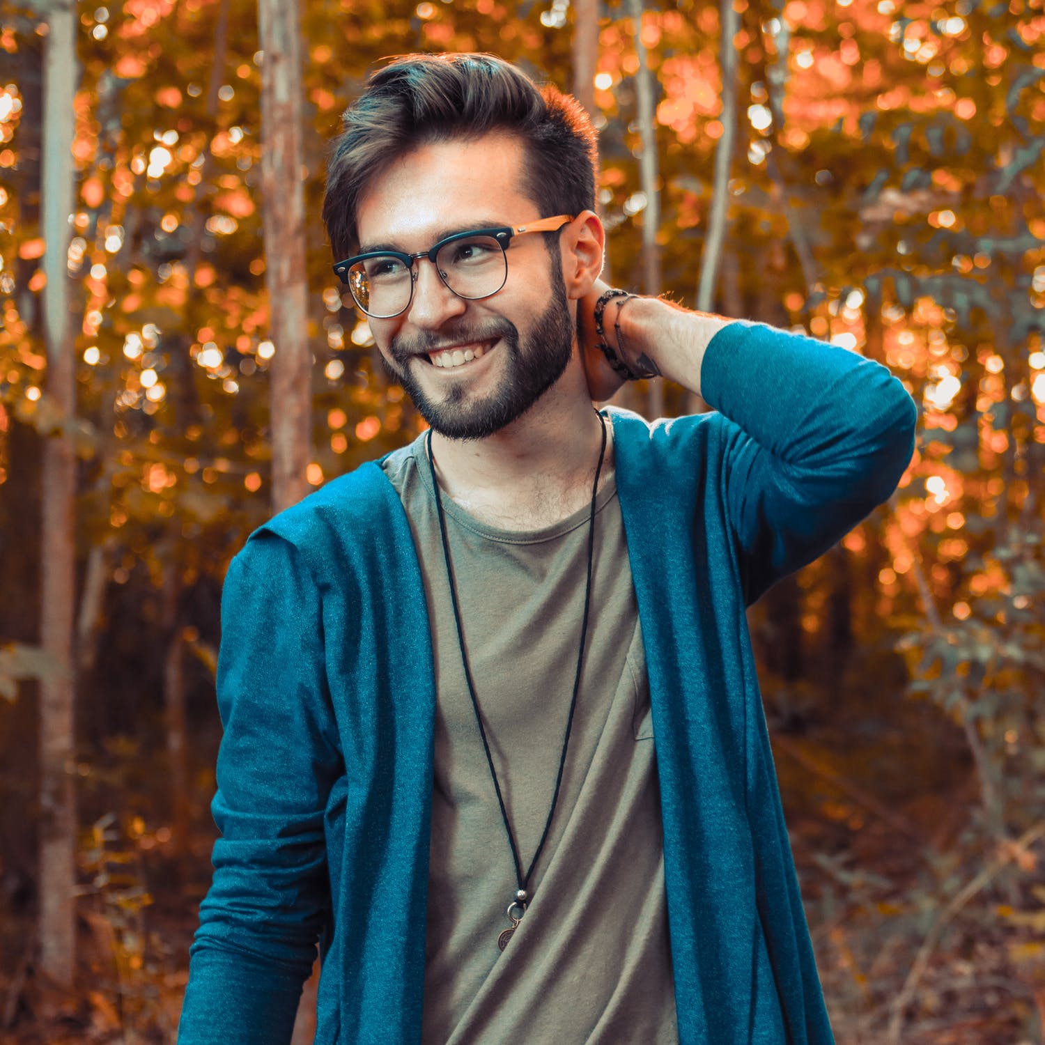 a man with glasses and a blue jacket with his hand on his head