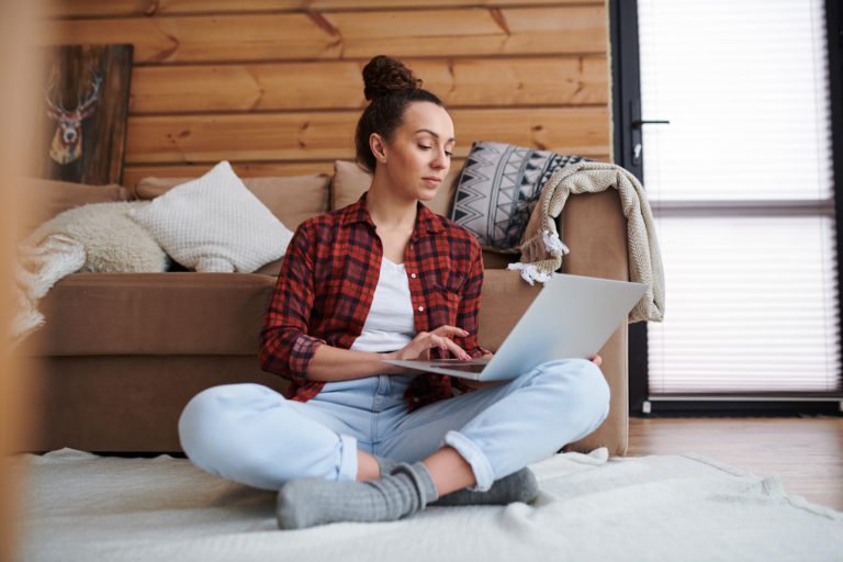 a person sitting on a bed looking at a laptop