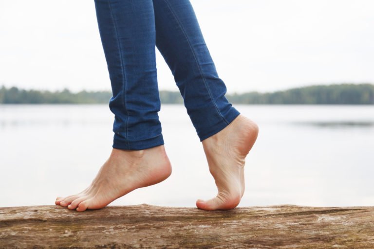 a person's feet on a rock by a body of water