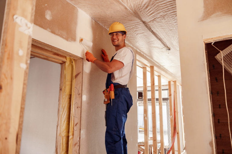 man painting wall in house under construction