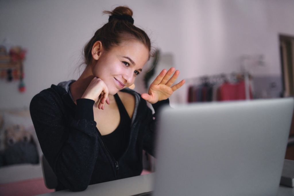 Beautiful happy young girl with laptop sitting and smiling, online dating concept