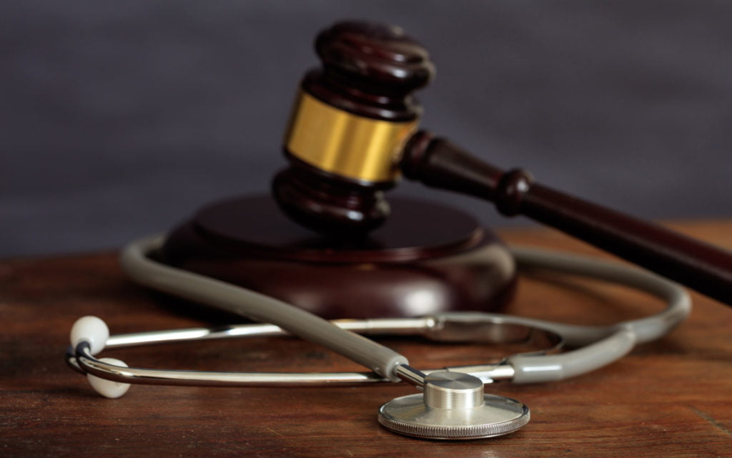 Judge gavel and a stethoscope on a wooden desk