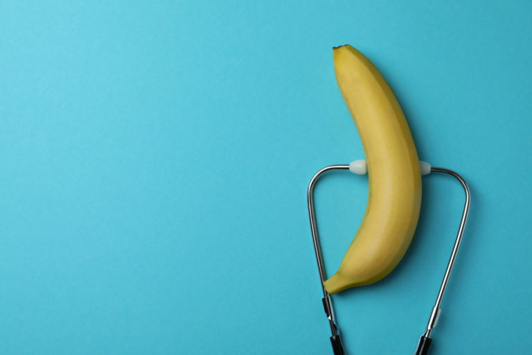 Banana and stethoscope on blue background, space for text