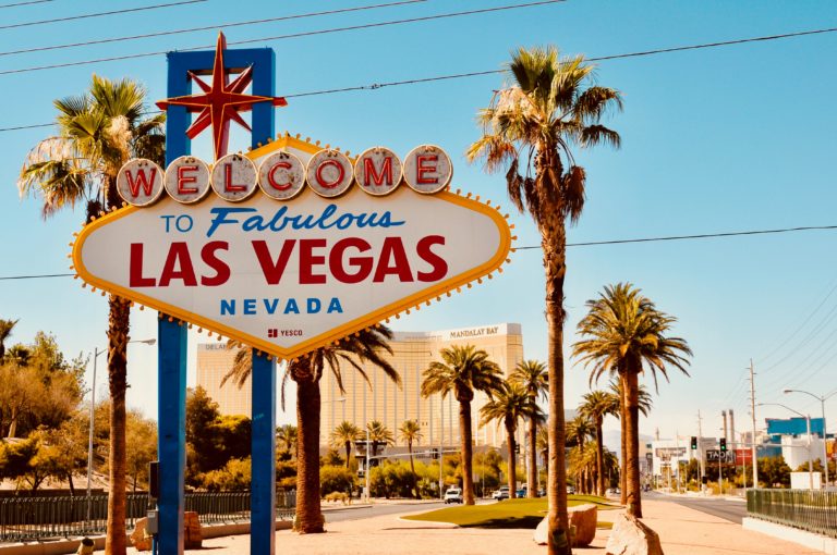 a sign with palm trees in the background with Welcome to Fabulous Las Vegas sign in the background