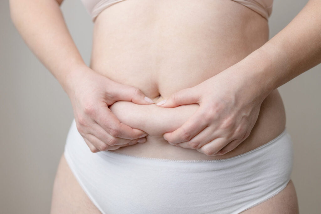 wellness, fat woman hand holding fat belly utc scaled