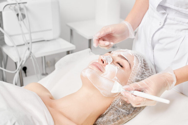 beauty, beautician applies cream mask on woman face for re utc