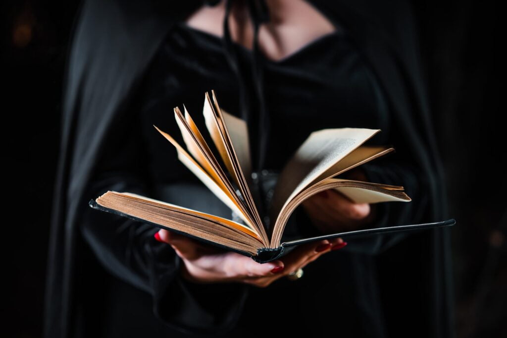 uncategorized, witch in black costume reading black magic book h utc scaled